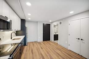 Harbourline Apartments, St Paul a renovated kitchen with white cabinets and a black door