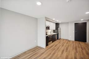 Harbourline Apartments, St Paul a living room and kitchen with a wood floor and white walls