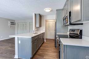A kitchen with a white counter top and wooden floors.