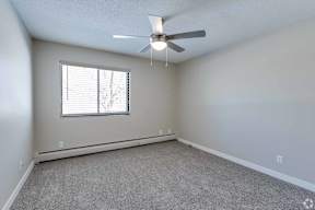 A room with a ceiling fan and a window with blinds.