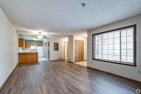 A spacious room with wooden floors and a large window.