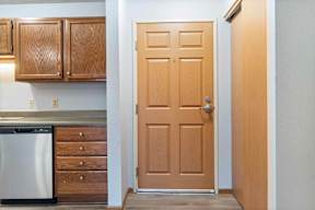 A kitchen with a wooden door and a dishwasher.