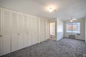 A room with white cupboards and a grey carpet.
