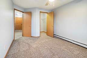A room with a carpeted floor and two wooden doors.