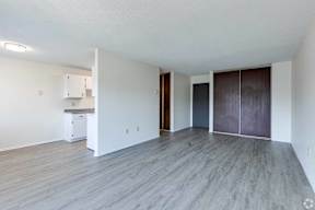 A spacious room with wooden flooring and white walls.