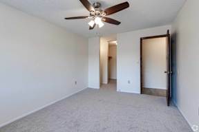 A room with a ceiling fan and carpeted floor.