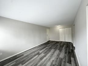 an empty living room with wood floors and white walls