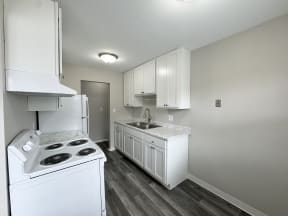 an empty kitchen with white appliances and white cabinets