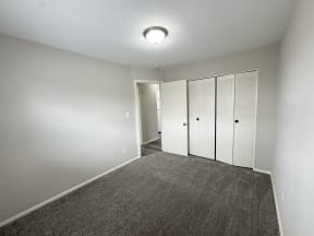an empty room with carpet and white closets