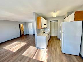 A kitchen with white appliances and wooden floors.