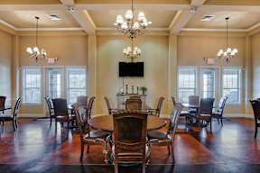 A large wooden dining table surrounded by chairs in a room with a chandelier.