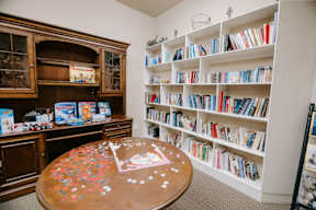 A room with a table, bookshelf, and a cabinet.