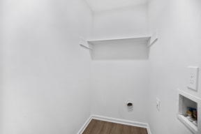 A small white room with a shelf and a wood floor.