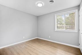 A room with a window covered by blinds and a light on the ceiling.