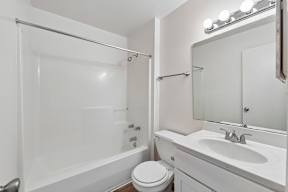 A white bathroom with a toilet, sink, and bathtub.