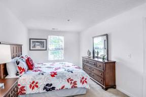 A bedroom with a floral bedspread and a wooden dresser.