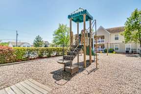 A playground with a green roofed slide and a wooden platform.