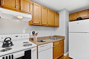 A kitchen with a white stove top oven and white dishwasher.