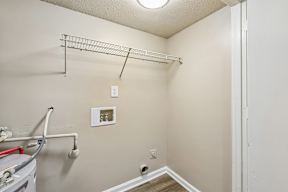 A small, empty room with a white door and a white wall.