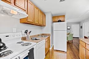 A kitchen with white appliances and wooden cabinets.