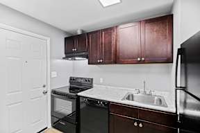 A kitchen with black appliances and brown cabinets.