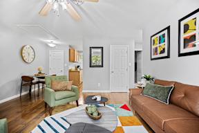 A living room with a brown couch, a green chair, and a wooden table.