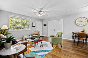 A living room with a ceiling fan and a clock on the wall.