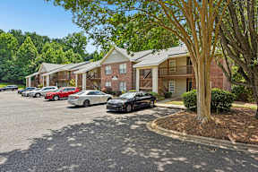 A parking lot with cars and apartment buildings in the background.
