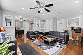 A living room with a grey couch and a ceiling fan.