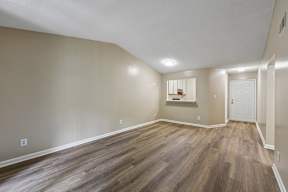 A room with wooden flooring and a window with blinds.