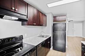 A kitchen with a black stove top oven and black fridge.