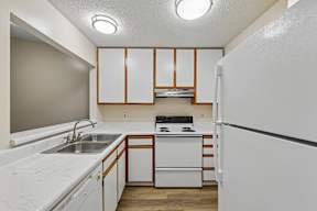A white kitchen with a white fridge and white countertops.