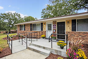 A small brick house with a black door and a small porch.