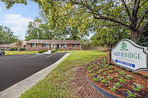 A sign for Southridge Nursing Home is in the foreground of a parking lot.