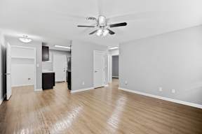 A room with a ceiling fan and wooden flooring.