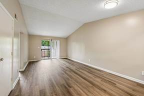 A room with wooden flooring and a sliding glass door.