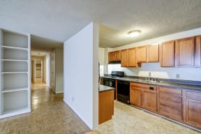 an empty kitchen with wooden cabinets and a black dishwasher