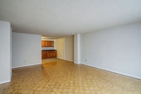an empty living room and kitchen with wood flooring and white walls