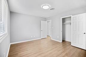 A room with a white door and a window with blinds.