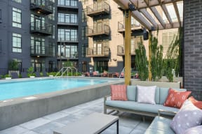 an outdoor lounge area with a couch and coffee table in front of an apartment building at Crossline, Columbus