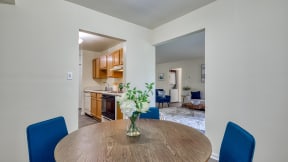 a dining room table with two blue chairs and a vase of flowers