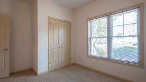 an empty bedroom with a large window and a door
