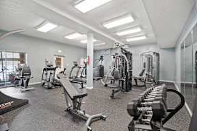 A gym with a variety of equipment including treadmills, weights, and exercise machines.