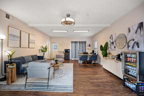 A modern living room with a grey sofa, a coffee table, and a kitchenette in the background.