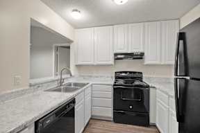 A kitchen with white cabinets and black appliances.