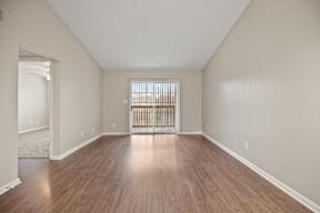 A room with wooden floors and a window with blinds.