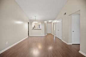 A long hallway with a chandelier and a door at the end.