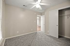 A room with a ceiling fan and a closet.