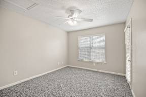 A room with a ceiling fan and a window with blinds.