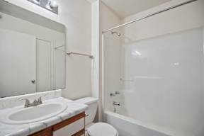 A white bathroom with a toilet, sink, and bathtub.